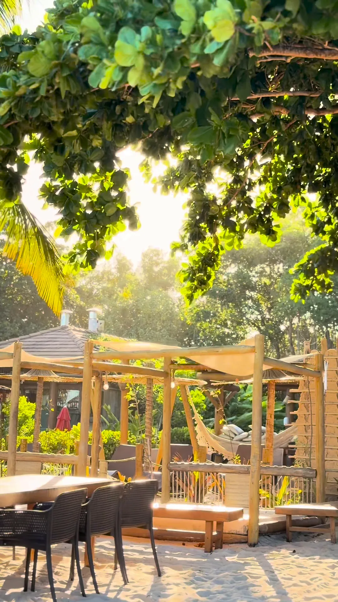 Cabanas de bambu com redes e mesas na areia de um beach club
